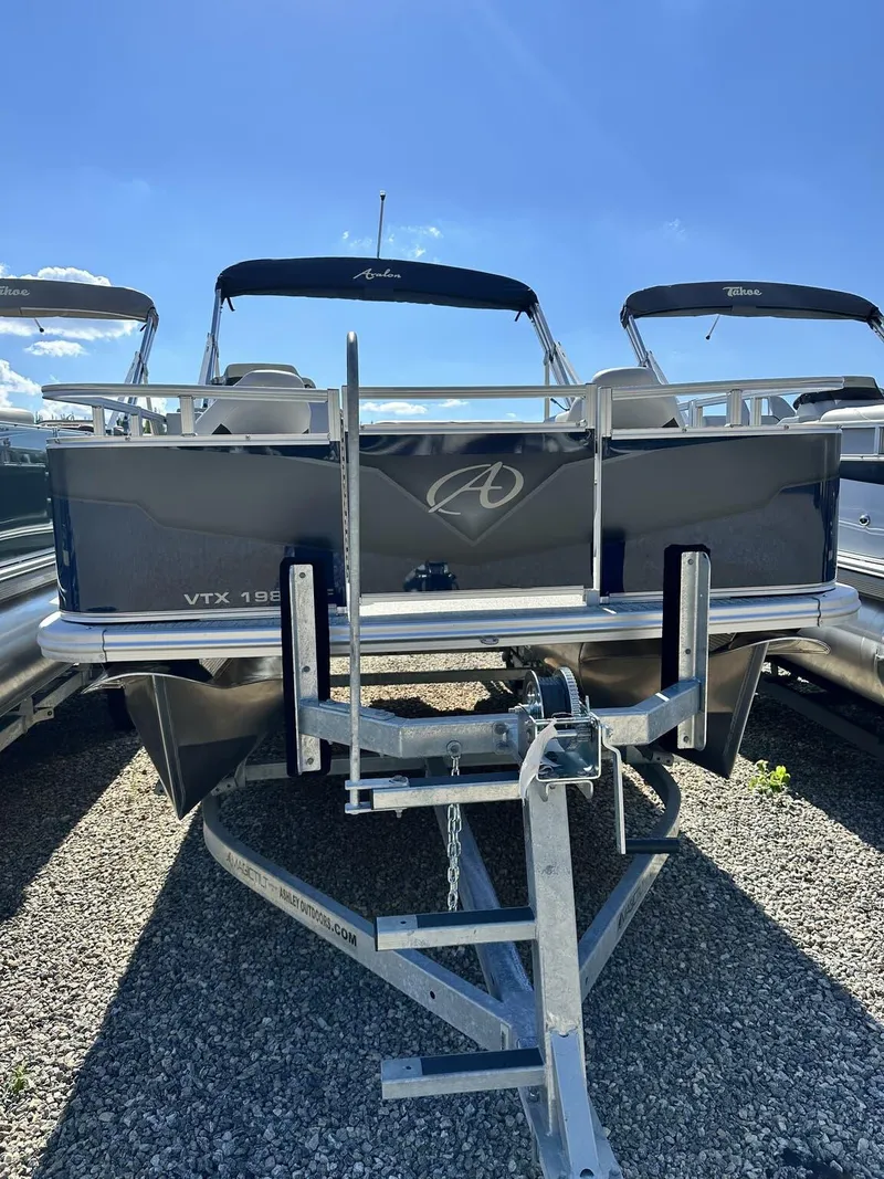 Slide: The Image of 2024 Avalon VTX Quad Fish 19 FT pontoon boat on a trailer under a clear blue sky. - 5