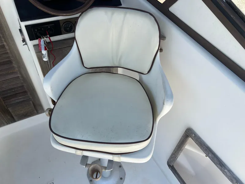 Slide: The Image of 1985 Mako 258 Cuddy boat captain's chair with white upholstery. - 10