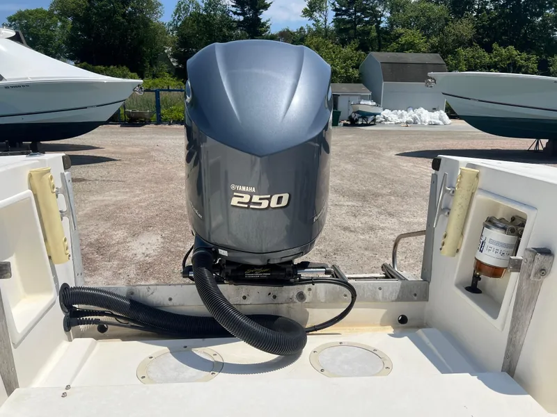 Slide: The Image of 1985 Mako 258 Cuddy with Yamaha 250 outboard motor in a boatyard. - 22