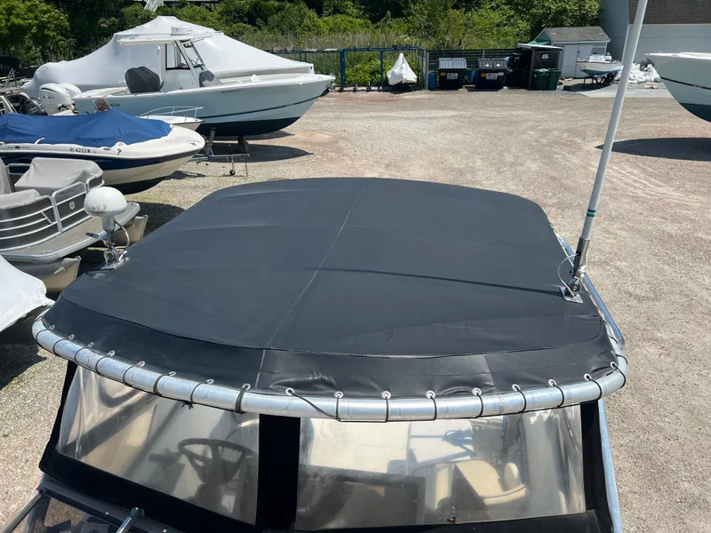 Slide: The Image of 1985 Mako 258 Cuddy boat with black canvas cover in a boatyard. - 30