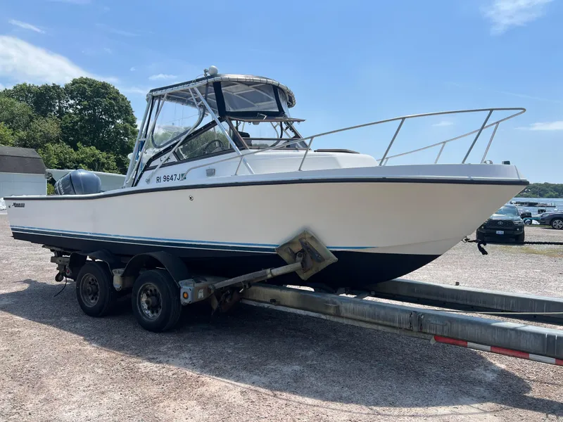 Slide: The Image of 1985 Mako 258 Cuddy boat on a trailer in a parking lot. - 5