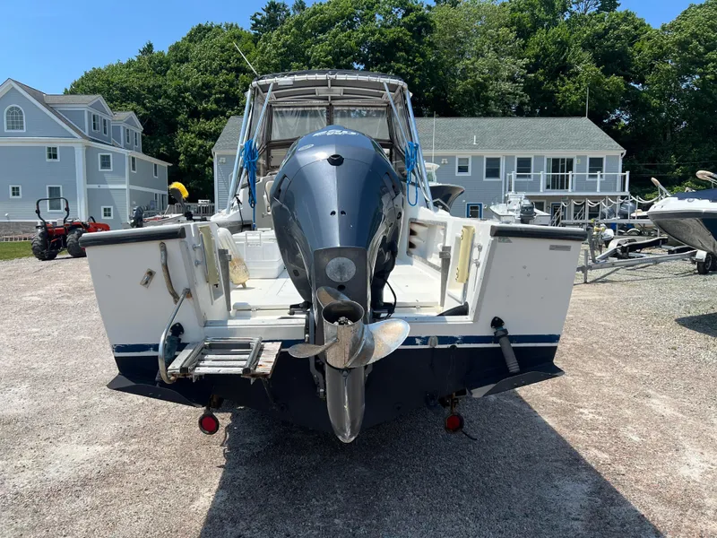 Slide: The Image of 1985 Mako 258 Cuddy boat with outboard motor, parked on gravel lot. - 7