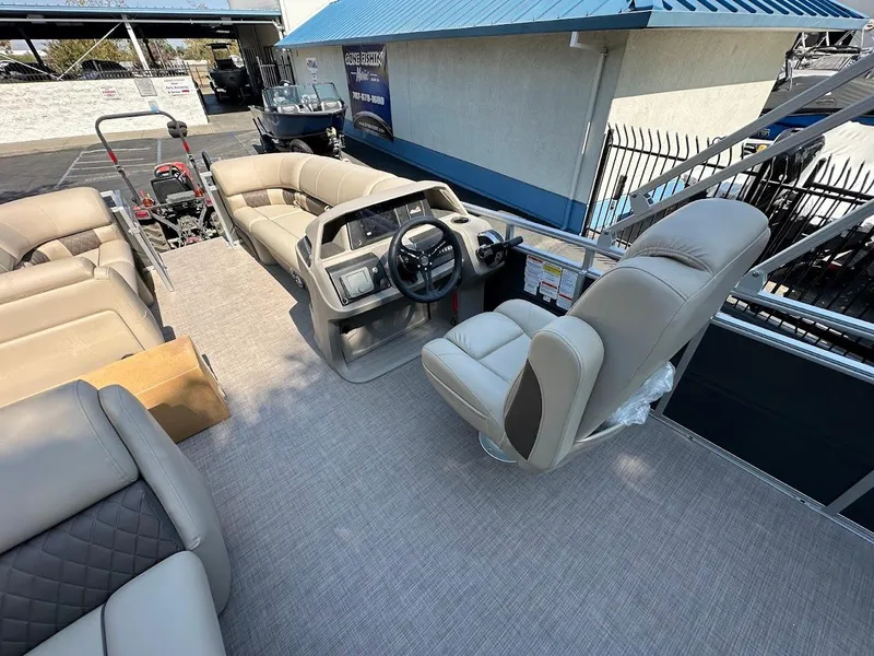 Slide: The Image of 2024 Sun Tracker Party Barge 20 DLX interior with beige seating and steering console. - 17