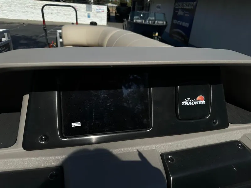 Slide: The Image of 2024 Sun Tracker Party Barge 20 DLX dashboard with logo and seating in background. - 20