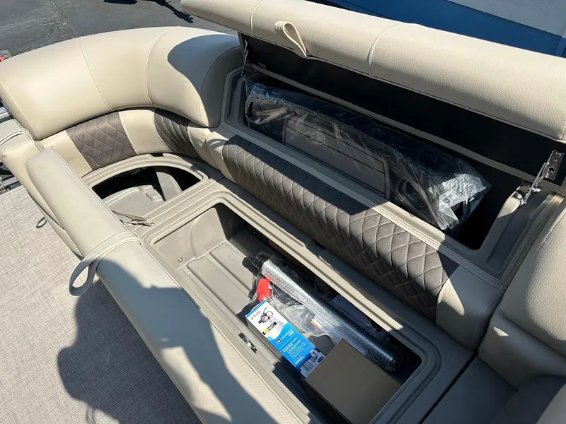 Slide: The Image of 2024 Sun Tracker Party Barge 20 DLX interior storage compartments, featuring beige and brown upholstery. - 24
