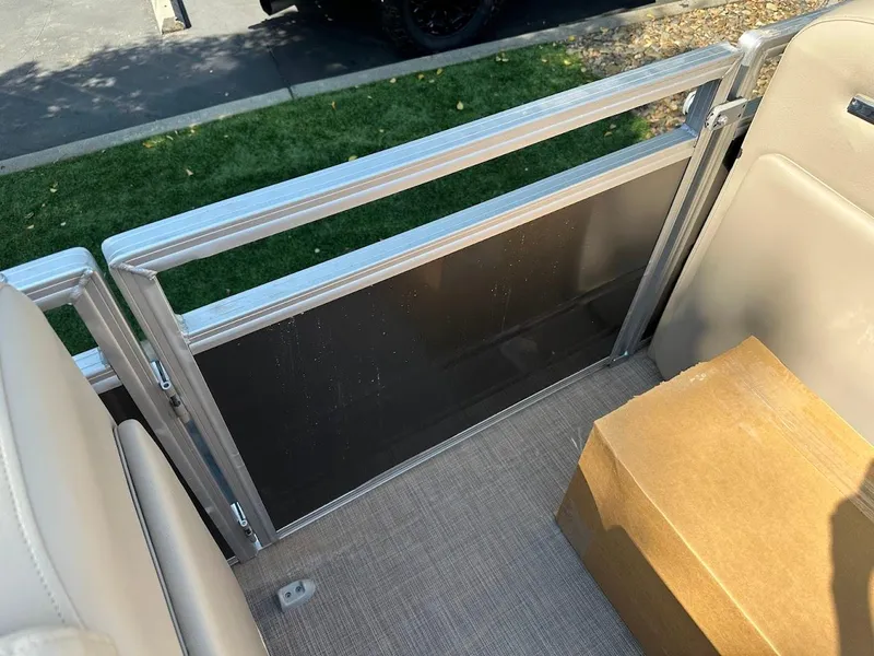 Slide: The Image of 2024 Sun Tracker Party Barge 20 DLX interior with beige seating and a cardboard box. - 31
