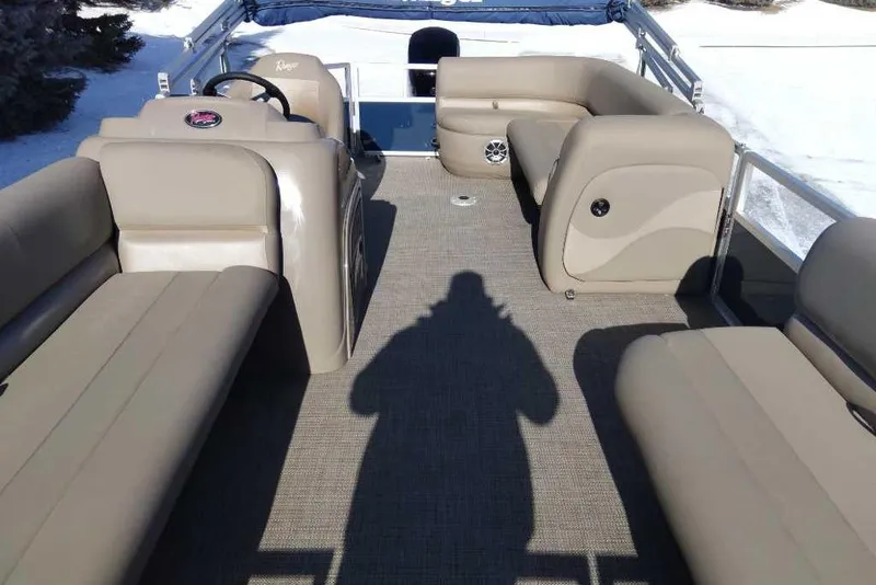 Slide: The Image of 2024 Ranger Reata 200C pontoon boat interior with beige seating and steering console. - 1