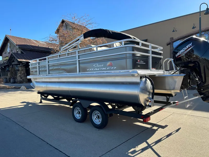 Slide: The Image of 2024 Sun Tracker Fishin' Barge 20 DLX pontoon boat on a trailer. - 2