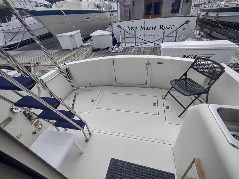 Slide: The Image of 1988 Tollycraft 34 Sport Sedan boat deck with seating and docked boats in background. - 26