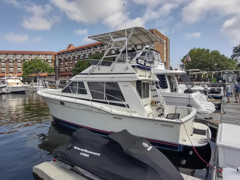 The Image of 1988 Tollycraft 34 Sport Sedan docked at a marina with other boats. - 0