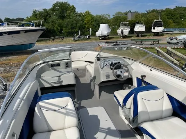 Slide: The Image of 2007 Bayliner Discovery 215 boat interior with white and blue seating, docked in a marina. - 10