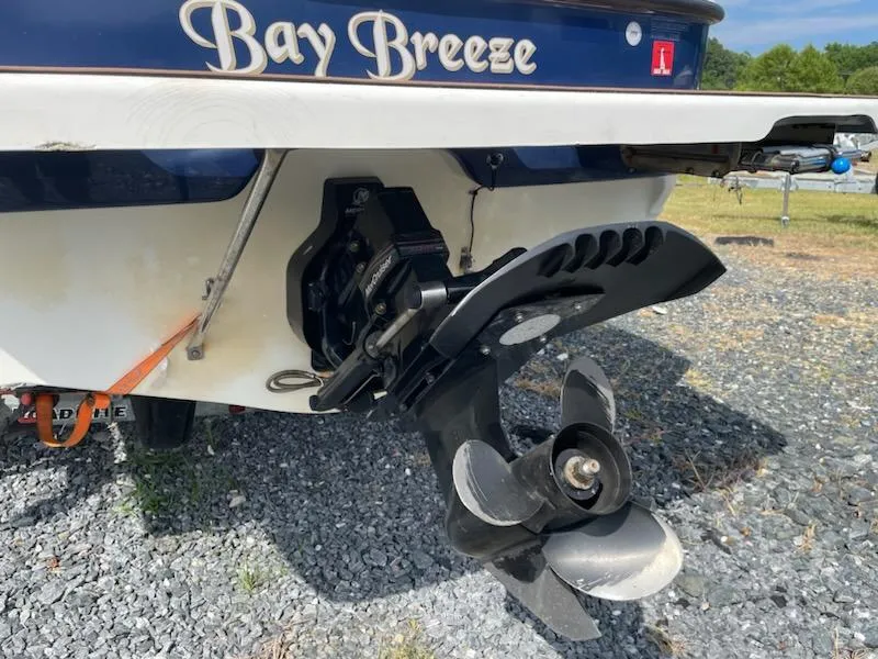 Slide: The Image of 2007 Bayliner Discovery 215 boat stern with propeller on gravel. - 22