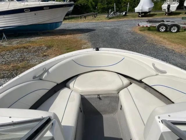 Slide: The Image of 2007 Bayliner Discovery 215 boat interior with white seating, parked on gravel. - 7