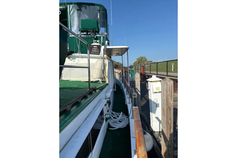 Slide: The Image of 1982 Monk 40 boat docked, green deck, clear sky, wooden posts, and coiled rope. - 38