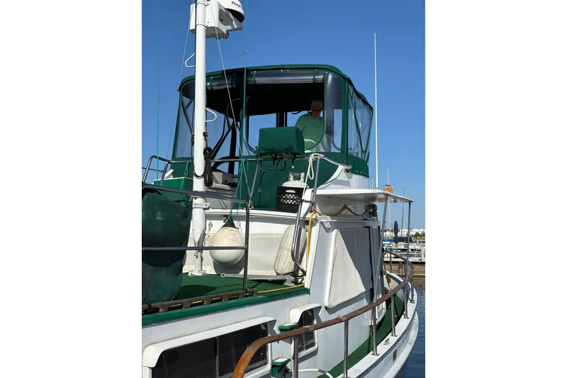 Slide: The Image of 1982 Monk 40 boat with green canopy, docked at marina under clear blue sky. - 39