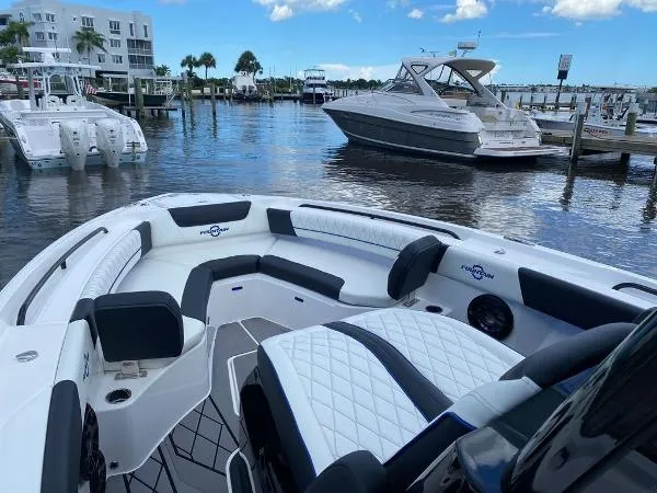 Slide: The Image of 2025 Fountain 32 NX boat interior with white and black seating, docked by wooden pier. - 9