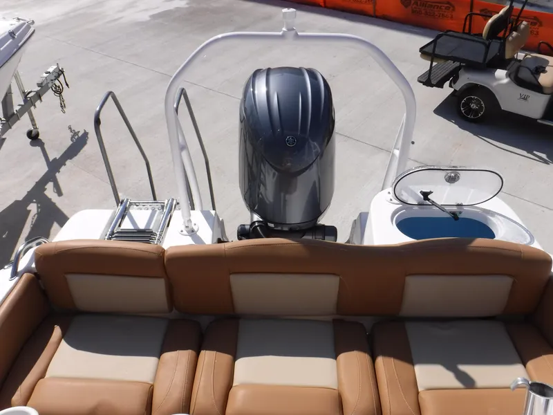 Slide: The Image of 2024 NauticStar 212 Legacy boat with tan seating and outboard motor, docked on concrete. - 10