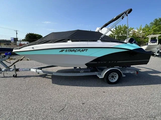 Slide: The Image of 2025 Starcraft SVX 171 OB boat on a trailer, covered and parked outdoors. - 7