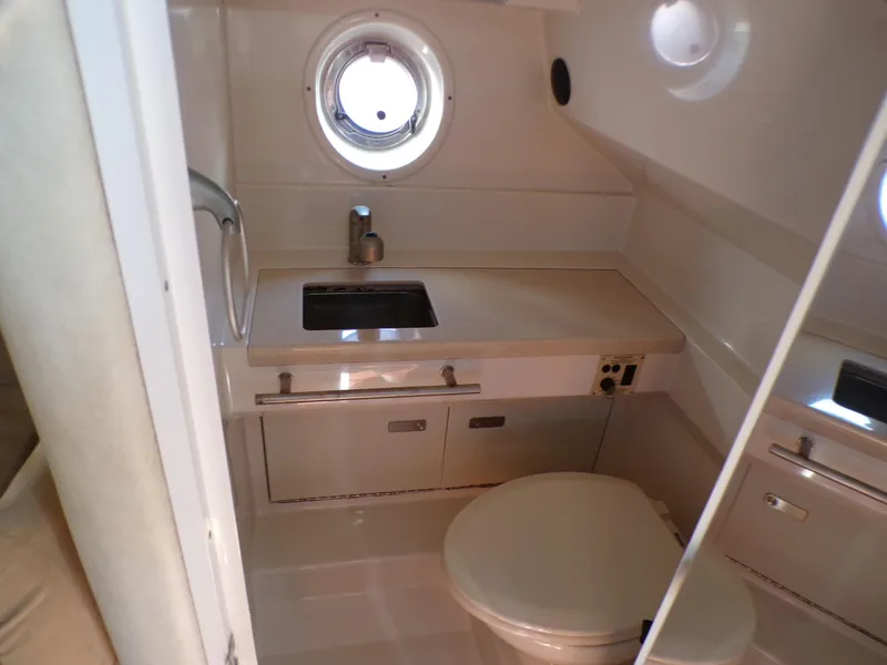 Slide: The Image of 2010 Sea Ray Sundancer bathroom with sink, toilet, and porthole window. - 18