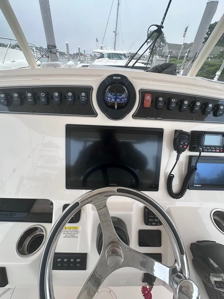 Slide: The Image of 2022 Grady-White Canyon 326 boat dashboard with steering wheel and navigation equipment. - 24