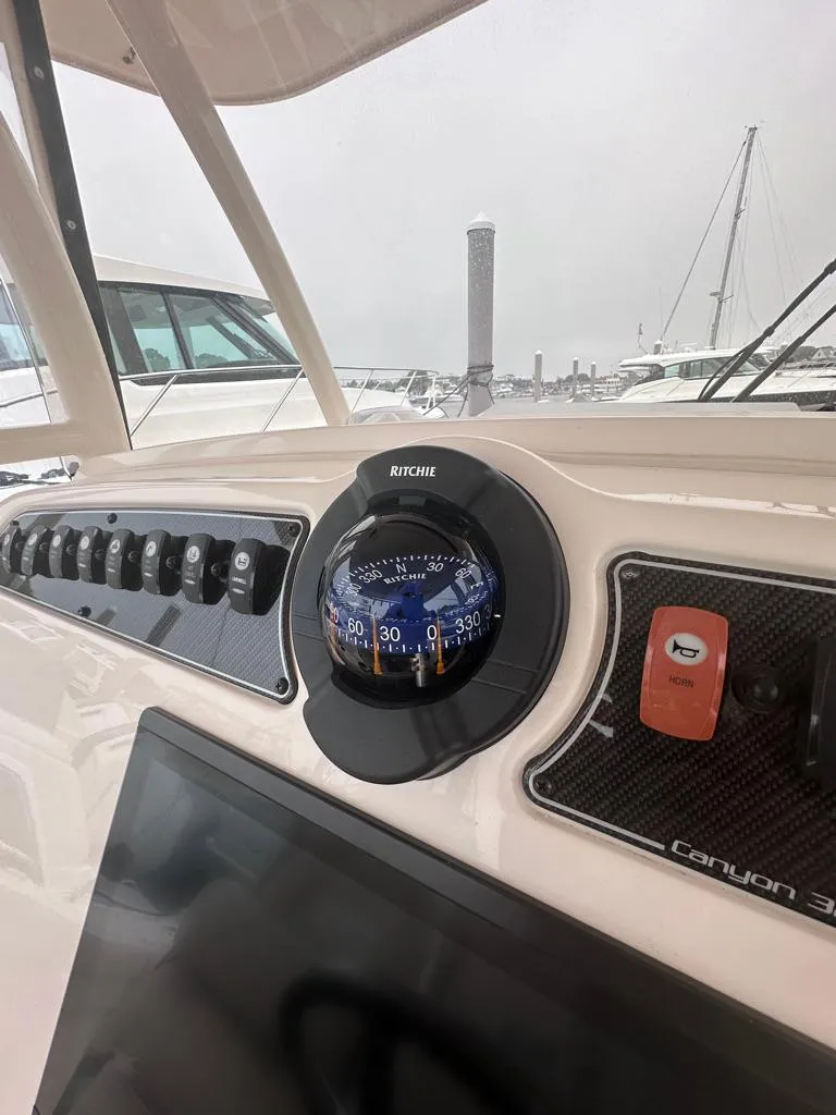 Slide: The Image of 2022 Grady-White Canyon 326 dashboard with compass and control panel. - 25