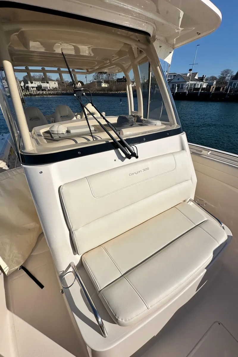 Slide: The Image of 2022 Grady-White Canyon 326 boat with cushioned seating and fishing rods, docked by the water. - 44