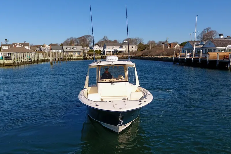Slide: The Image of 2022 Grady-White Canyon 326 boat navigating a calm harbor under clear blue skies. - 11