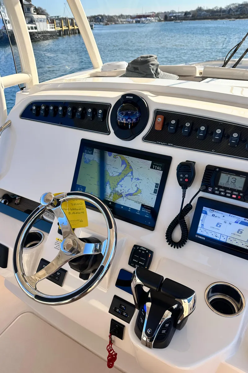 Slide: The Image of 2022 Grady-White Canyon 326 helm with navigation screens and controls, overlooking serene water. - 36