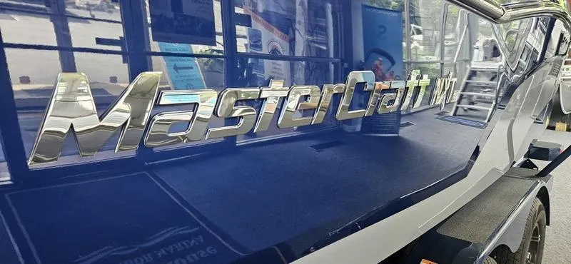 Slide: The Image of 2025 MasterCraft NXT22 boat with chrome logo on blue hull. - 2