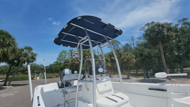 Slide: The Image of 2011 Carolina Skiff 178 DLV boat with T-top, parked near palm trees. - 25