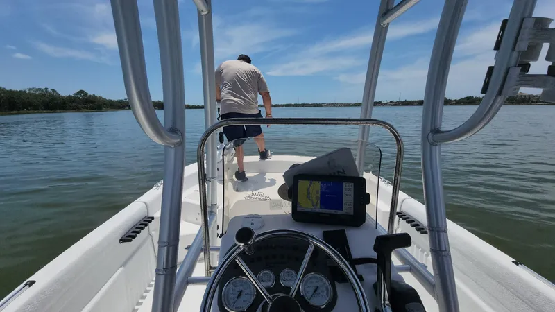 Slide: The Image of 2011 Carolina Skiff 178 DLV on calm water, person standing at the bow, clear sky. - 3
