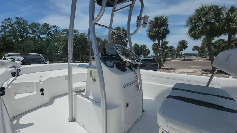Slide: The Image of 2011 Carolina Skiff 178 DLV boat interior with steering console, palm trees in background. - 33