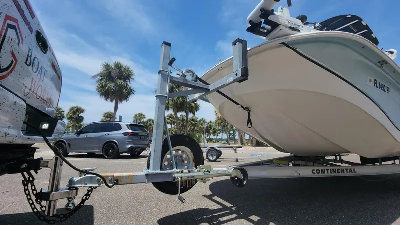 Slide: The Image of 2011 Carolina Skiff 178 DLV boat on trailer, parked near palm trees under a clear blue sky. - 42