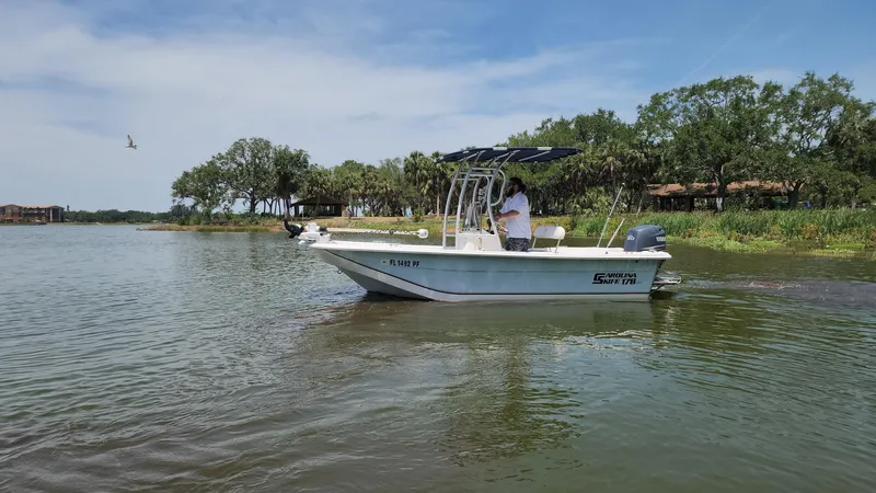 Slide: The Image of 2011 Carolina Skiff 178 DLV boat cruising on a calm river with lush greenery. - 47
