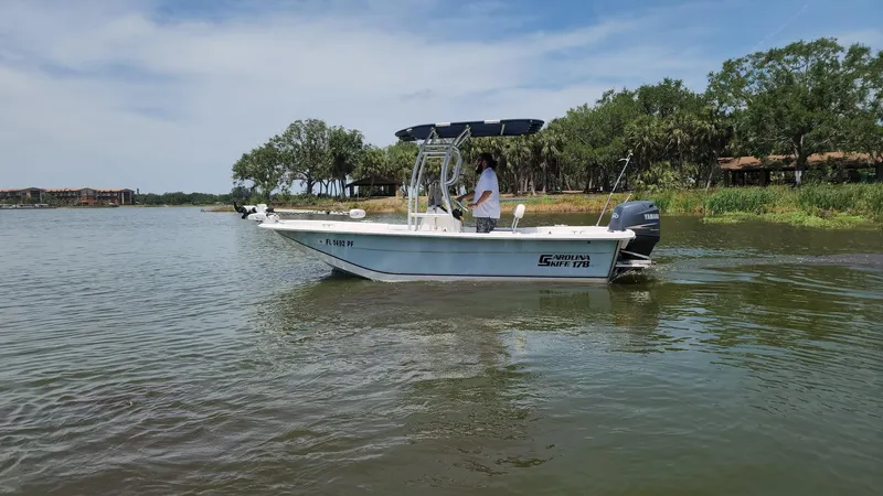Slide: The Image of 2011 Carolina Skiff 178 DLV boat on calm water, with trees in the background. - 49