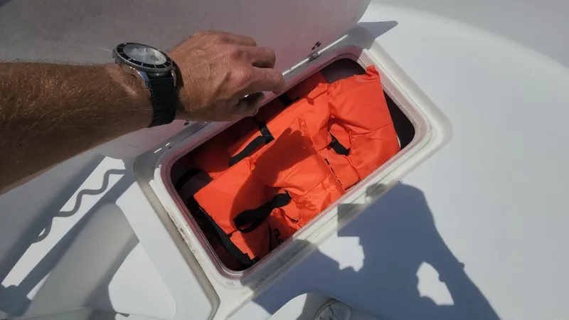 Slide: The Image of Hand opening storage compartment with life jackets on a 2011 Carolina Skiff 178 DLV boat. - 7