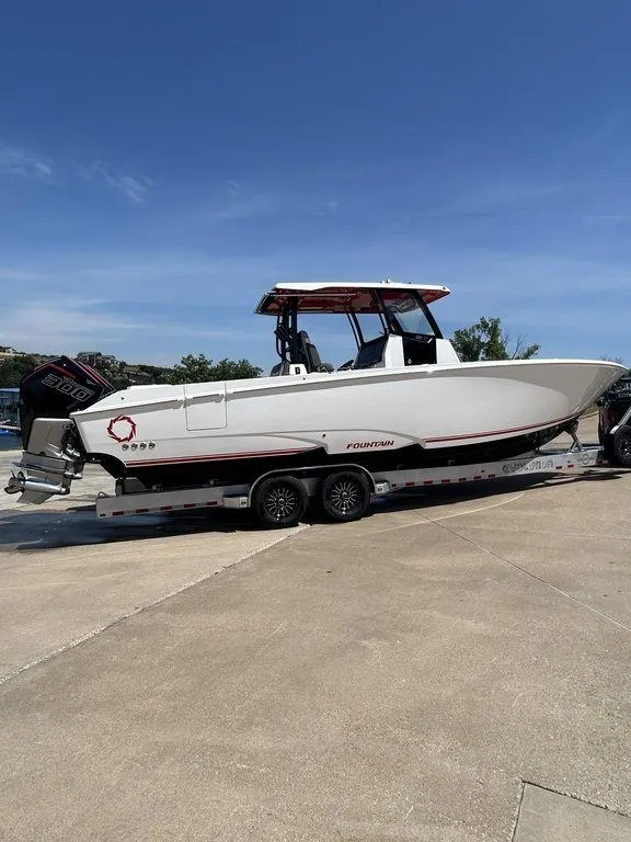 Slide: The Image of 2024 Fountain 32 NX boat on a trailer under a clear blue sky. - 10