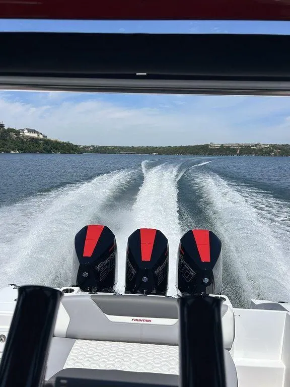 Slide: The Image of 2024 Fountain 32 NX boat with triple outboard engines cruising on a lake. - 13
