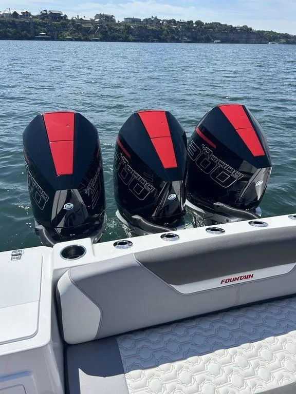 Slide: The Image of 2024 Fountain 32 NX boat with triple outboard engines on a calm lake. - 18