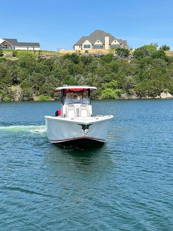 Slide: The Image of 2024 Fountain 32 NX boat cruising on a lake with houses in the background. - 3