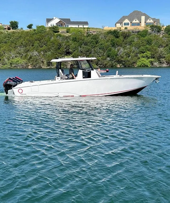 Slide: The Image of 2024 Fountain 32 NX boat cruising on a lake with houses in the background. - 4