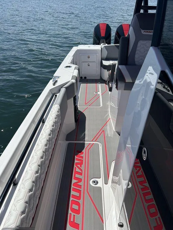 Slide: The Image of 2024 Fountain 32 NX boat interior with red accents on the deck, docked on water. - 9