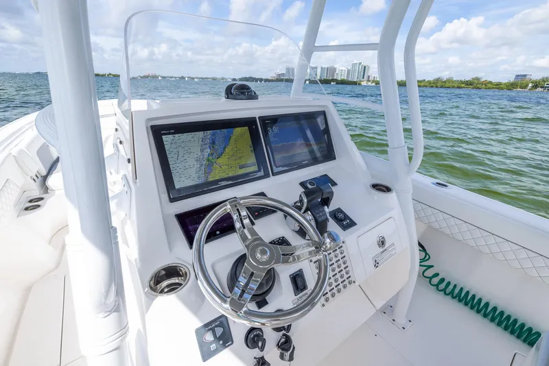 Slide: The Image of 2019 Intrepid 327 Center Console boat dashboard with navigation screens and steering wheel. - 44