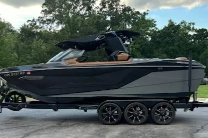 Slide: The Image of 2020 Nautique P23 boat on a trailer, black and gray exterior, parked outdoors. - 13