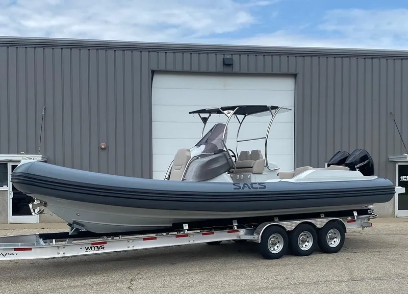 The Image of 2024 SACS Strider 900 boat on a trailer outside a warehouse. - 0