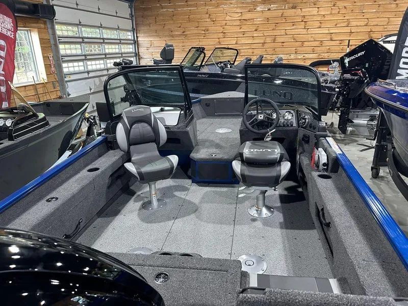 Slide: The Image of 2025 Lund Adventure 1775 Sport boat interior with seating and steering console in showroom. - 3