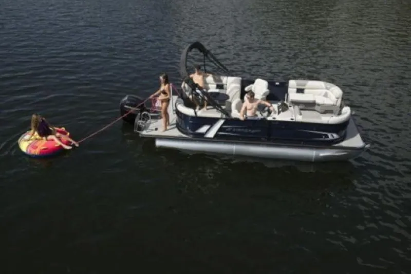 Slide: The Image of 2025 Starcraft EXS 1 pontoon boat towing a person on a tube in a lake. - 13