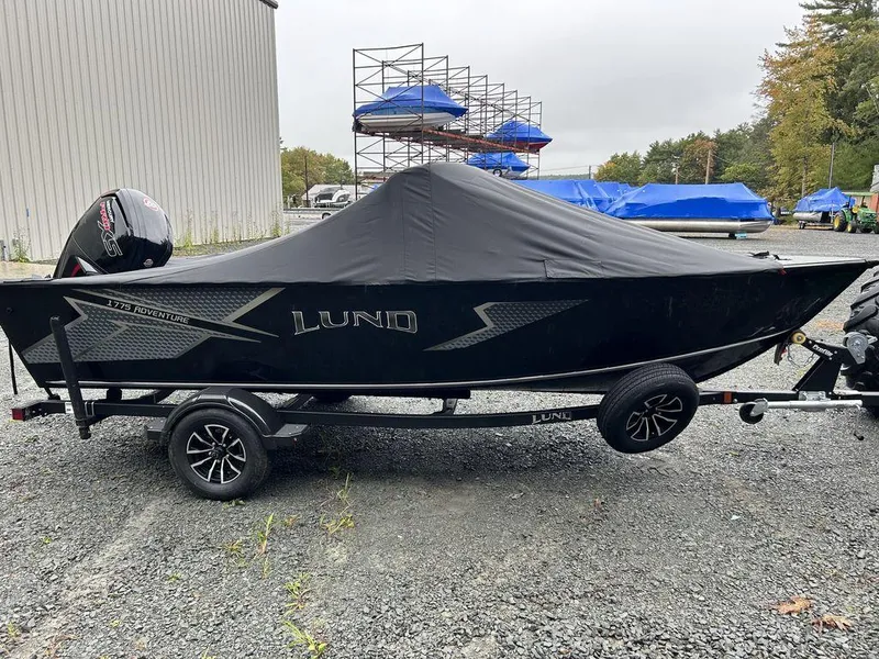 Slide: The Image of 2025 Lund Adventure 1775 Sport boat covered on trailer, outdoor storage area. - 4