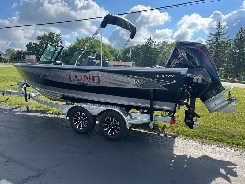 Slide: The Image of 2025 Lund 1975 Tyee fishing boat on a trailer, parked outdoors. - 2