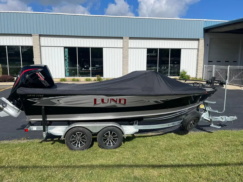 Slide: The Image of 2025 Lund 1975 Tyee boat on a trailer, covered, parked outside a building. - 29